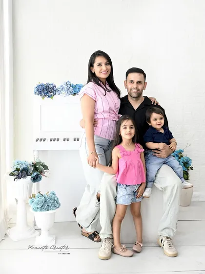 A classic family portrait with a clean, modern aesthetic. The simple white background with pops of blue keeps the focus on the family's happy faces.