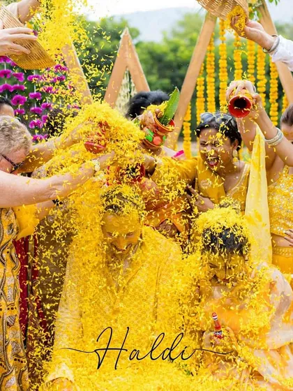 A Haldi ceremony where everyone joins in! This photo captures the communal joy of the ritual, with family and friends showering the couple with love and flowers.