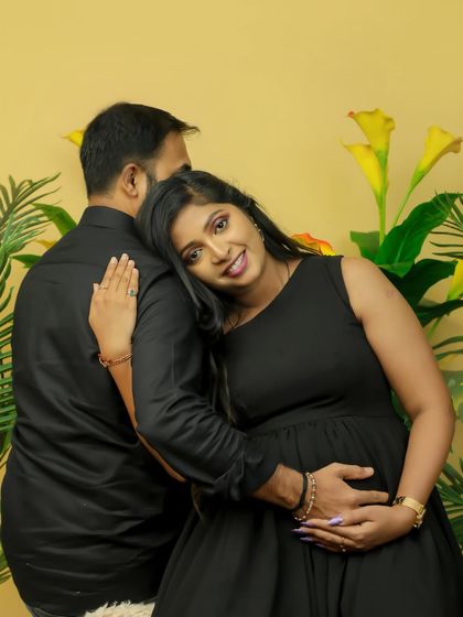 A sweet moment of connection between a couple. The mother-to-be looks radiant in a simple black dress, creating a classic and timeless studio portrait.
