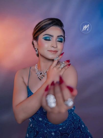 This shot focuses on the dramatic eye makeup and the stunning rings and necklace that complement the blue rental gown.
