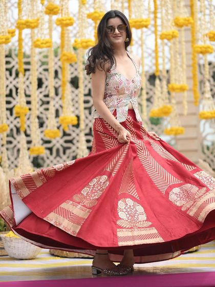 A full, twirling shot of the client's custom red brocade lehenga. The movement and richness of the fabric make it a perfect choice for a wedding celebration.
