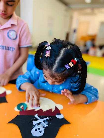Two children working near each other, one adding the final touches to a pirate craft.