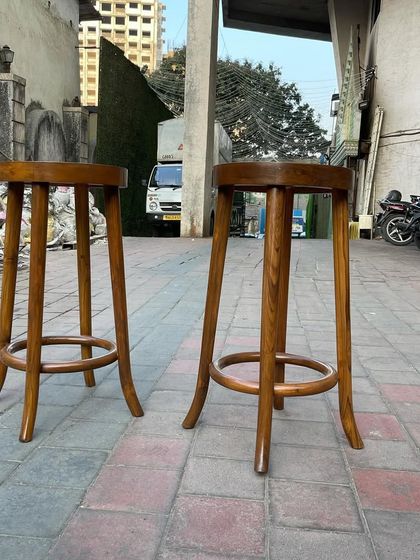 A view of the bar stools from a lower angle, emphasizing the solid wood construction and the footrest ring that adds both stability and comfort.