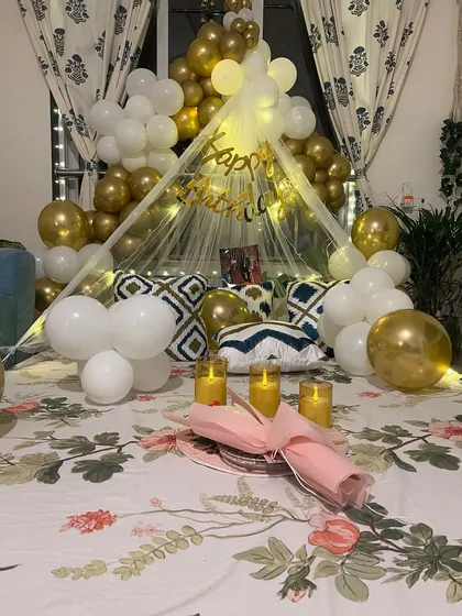 For a truly personal celebration, I designed this romantic birthday surprise in a client's home in Govandi. A beautiful canopy tent over the bed, adorned with fairy lights and a cascade of white and gold balloons, created a cozy and magical space for a private and unforgettable evening.