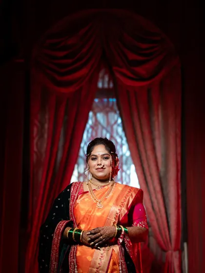 A beautiful portrait of the bride framed by a dramatic red curtain. The lighting and composition give this photo a regal and theatrical quality.