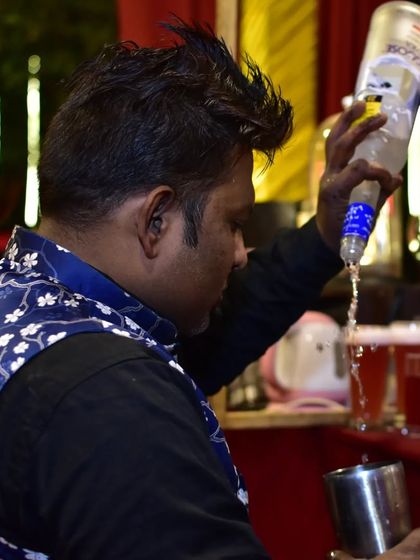 A bartender carefully pouring from a bottle of Absolut vodka. Precision and attention to detail are key to making consistently great drinks.