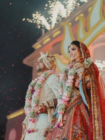 Love, laughter, and happily ever after. A beautiful shot of the couple during their varmala ceremony, with fireworks lighting up the sky behind them.