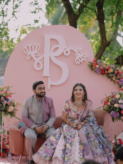 The couple seated at their beautifully designed stage, with a custom monogram and floral arrangements.