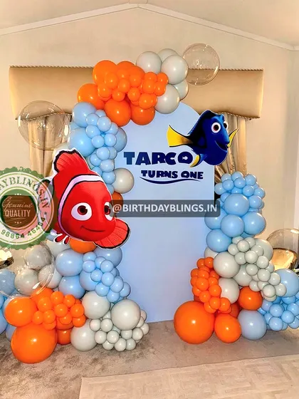A Finding Nemo first birthday party. The blue, white, and orange balloons mimic the ocean and clownfish, with cutouts of Nemo and Dory.