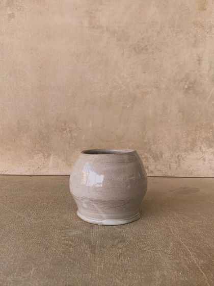 A small, round vase with a soft, creamy white glaze. Its simple, classic shape makes it a versatile piece for any home.