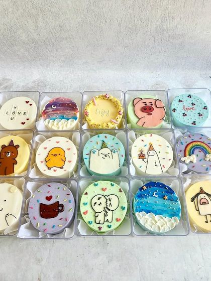 A collection of today's mini bento cakes, with a fun mix of designs like a coffee cup, a rainbow, and cute animal characters.