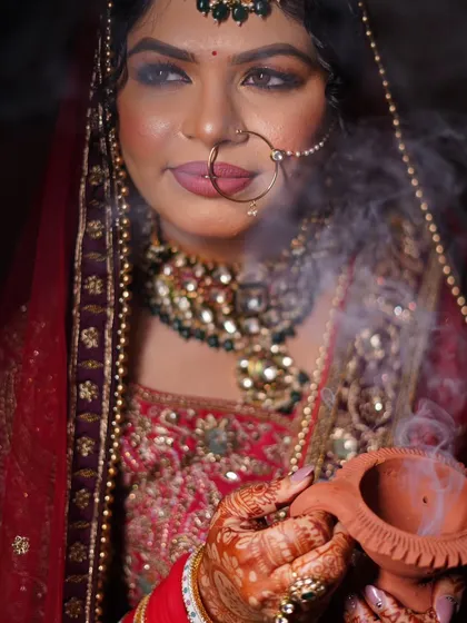 A close-up portrait with the diya, focusing on the bride's contemplative expression and the beautiful details of her nath and makeup.
