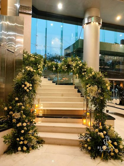 The full view of the grand staircase, transformed into a romantic pathway. The cascading flowers and the warm glow of the candles create a fairytale entrance for the couple and their guests.