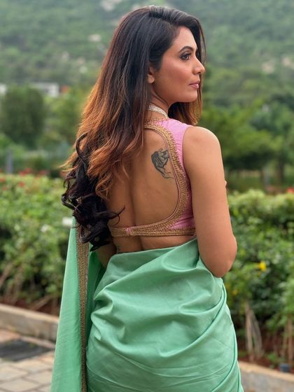 The back view of Shwetha's blouse, featuring a deep, open-back design with delicate gold border work.