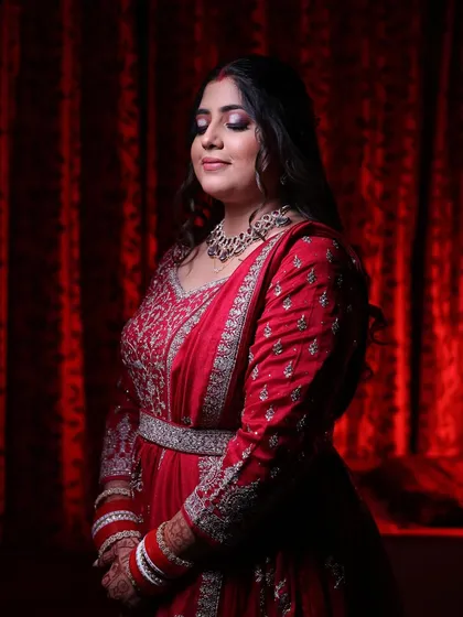 An artistic shot against a red backdrop, highlighting the elegance of her outfit and makeup.