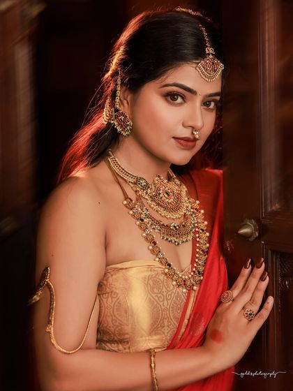 A regal portrait series inspired by the queens of Tulunadu. The model is adorned in a stunning red saree and antique-style jewelry, captured in a heritage location to enhance the royal theme.