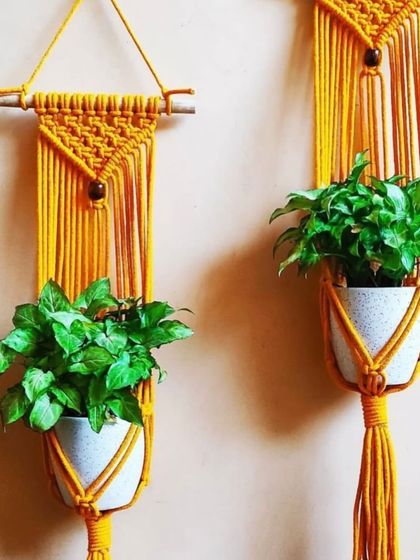 A close-up of my single plant hangers in a cheerful yellow. The design features wooden beads and sturdy knots to securely cradle your favorite potted plants.
