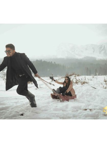 The groom playfully pulls the bride on a sled, a moment of pure fun and laughter. These are the unscripted memories that make a shoot special.