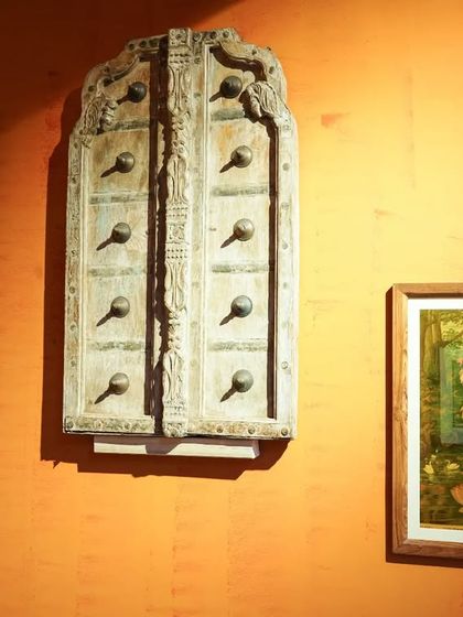 Wall decor details from the puja, including an antique wooden door and a traditional Ravi Varma painting of Lakshmi, blending art and spirituality.