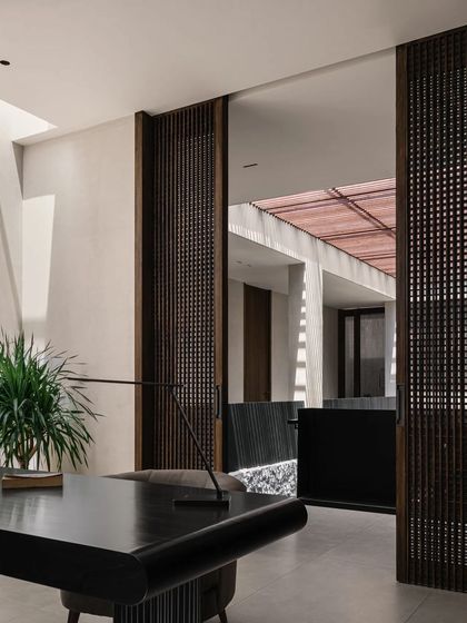 The home office, seen through sliding wooden screens. This design allows the workspace to be integrated with the rest of the home or closed off for privacy, offering flexibility and a connection to the central courtyard.