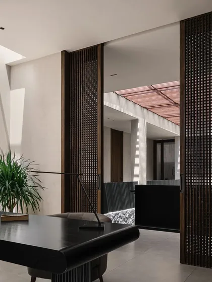 The home office, seen through sliding wooden screens. This design allows the workspace to be integrated with the rest of the home or closed off for privacy, offering flexibility and a connection to the central courtyard.