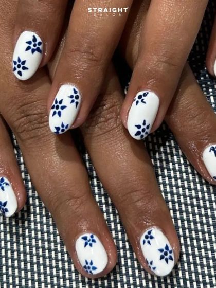 A crisp white manicure with a hand-painted blue floral pattern. The design is inspired by classic blue and white porcelain, giving it a timeless and elegant feel.
