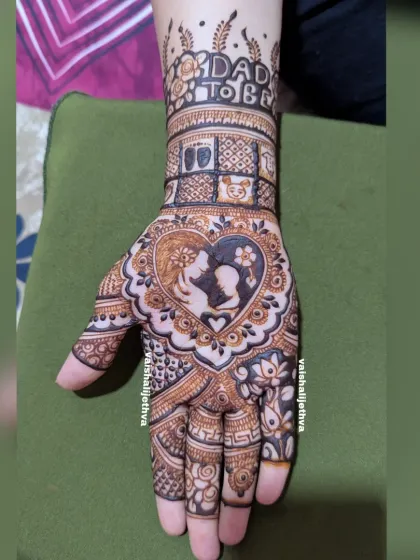A beautiful design for a dad-to-be. This mehndi features a silhouette of a couple holding a baby, surrounded by lotus flowers and baby-related motifs.