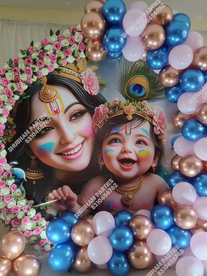 A beautiful Krishna themed decoration with a circular backdrop featuring mother Yashoda and baby Krishna, framed by pink, blue, and gold balloons.