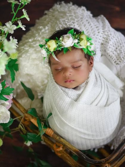 A beautiful setup featuring a basket of flowers next to the baby, who is wearing a delicate floral crown.