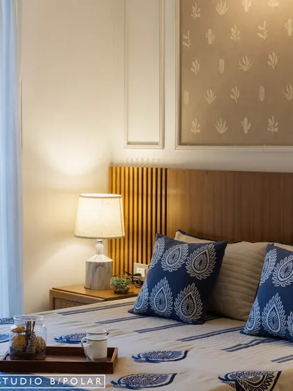 A different bedroom in the same residence features a subtle cactus-print wallpaper and bedding with traditional Indian block-print patterns. The mix of patterns and textures creates a layered and personal feel.
