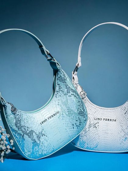 This shot displays two color variations of a snakeskin print shoulder bag against a cool blue background. Placing them together helps customers compare options while creating a balanced and aesthetically pleasing composition.