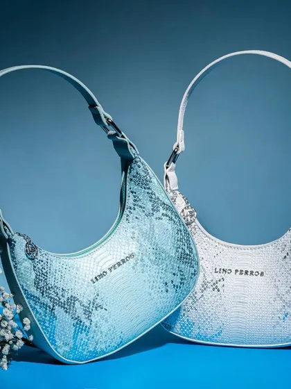 A clean, styled shot of two snakeskin-patterned shoulder bags against a cool blue background. This image is perfect for showcasing product variations in a sleek, modern way.