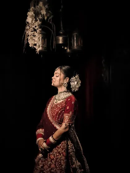 A low-light portrait of a bride standing under antique lanterns, her eyes closed, creating a moment of quiet contemplation.