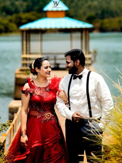 This couple looks effortlessly elegant walking by the water. The red gown with illusion details and the partner's classic white shirt and suspenders are perfect for a romantic, rustic shoot.