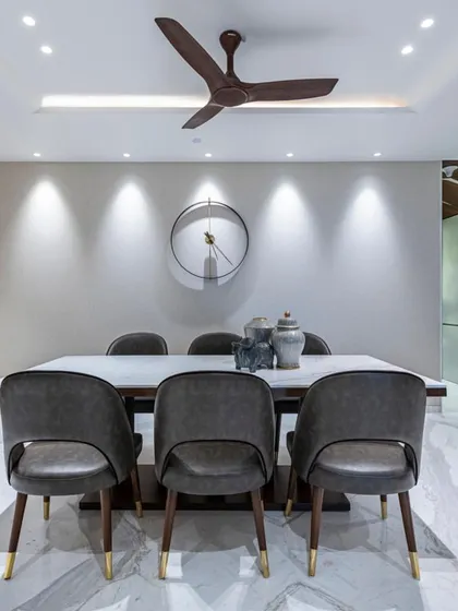 The dining set in the Filigree House, viewed front-on. The composition is balanced and serene, with a large, minimalist clock on the wall adding a touch of graphic interest.