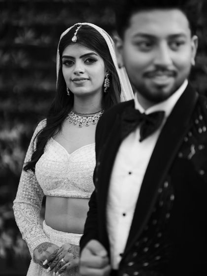 A striking black and white portrait, with the bride in sharp focus and the groom slightly out of focus. This artistic composition adds a layer of storytelling to the image.