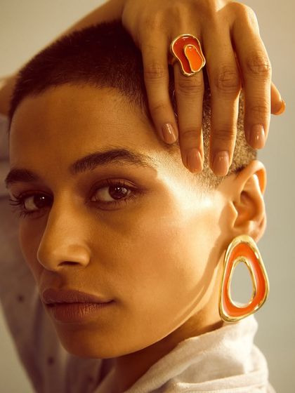Another powerful portrait from the Voyce campaign. The model's hand frames her face, drawing attention to both the ring and the large, colorful earrings.