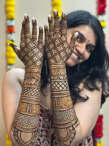 A happy client showcasing her beautiful grid pattern mehendi. Her smile is a testament to her satisfaction with the design.