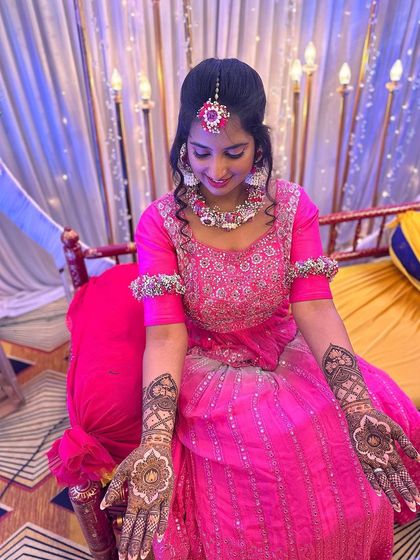 A bride in a vibrant pink dress, her hands displaying elegant mandala designs.