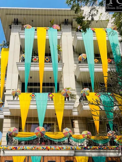 I can turn any building into a 'shadi vala ghar'. Here, I used vibrant yellow and teal drapes with decorative umbrellas and traditional hangings to create a festive and welcoming facade for a pre-wedding ceremony.