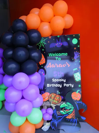 "Welcome to Aarav's Spooky 5th Birthday Party!" This Halloween-themed welcome sign with witches, pumpkins, and bats sets a fun and spooky mood.