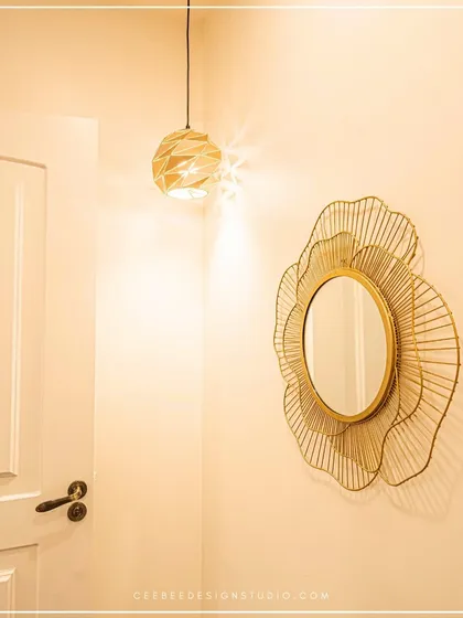A corner detail showing a decorative gold mirror and a modern pendant light, highlighting the importance of lighting and accessories.