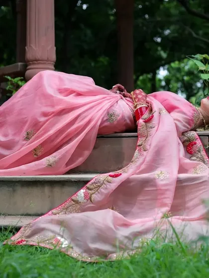 A serene shot of the model resting on stone steps, surrounded by lush greenery.