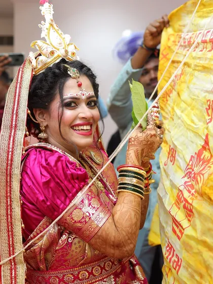 A joyful, candid moment of the Bengali bride during the wedding rituals. Her makeup stays flawless and radiant throughout the event.