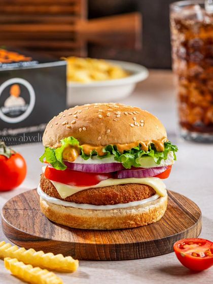 A close-up of a loaded veggie burger, showcasing its layers of patty, cheese, lettuce, and tomato for a cafe menu.