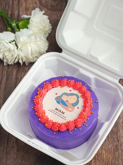 A sweet bento cake for Mother's Day. This purple cake features a cute edible print of a mother and child, surrounded by a border of pink buttercream frosting.