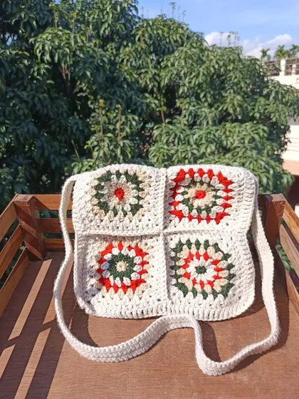 A classic granny square crossbody bag with a festive red, green, and white color scheme. This timeless design is always in style.
