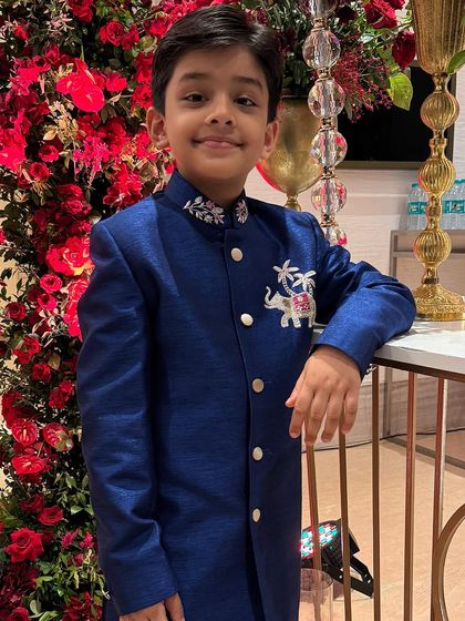 Looking like a little royal in our hand-worked blue sherwani. The intricate elephant motif on the chest and detailed collar embroidery add a touch of regal charm to this standout wedding outfit.