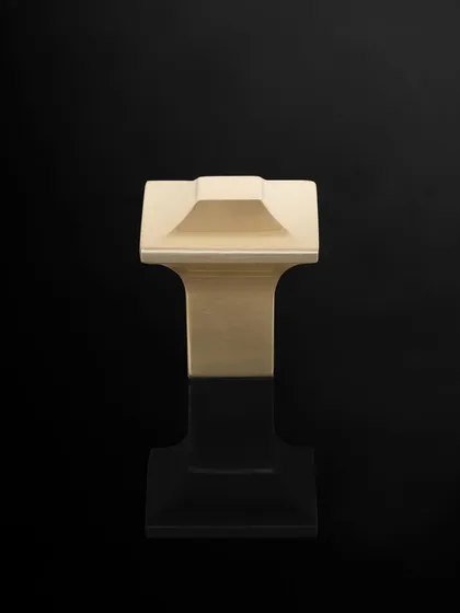 A product shot of a uniquely shaped cabinet knob against a solid black background. The lighting carves out the product's geometric form, emphasizing its design.