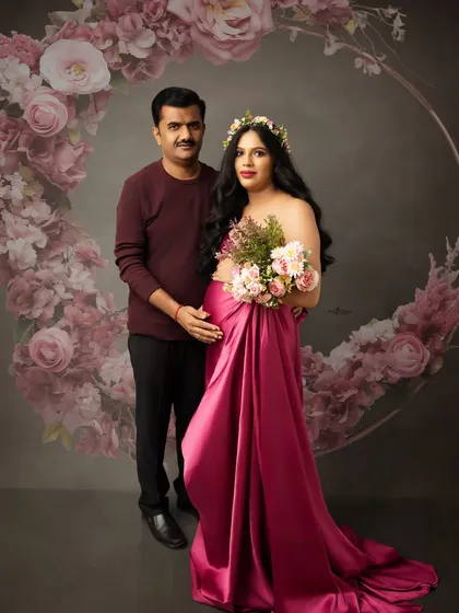 A romantic portrait featuring a beautiful flowing gown. The mother-to-be is framed by a floral wreath, creating a soft yet glamorous image that celebrates her pregnancy.